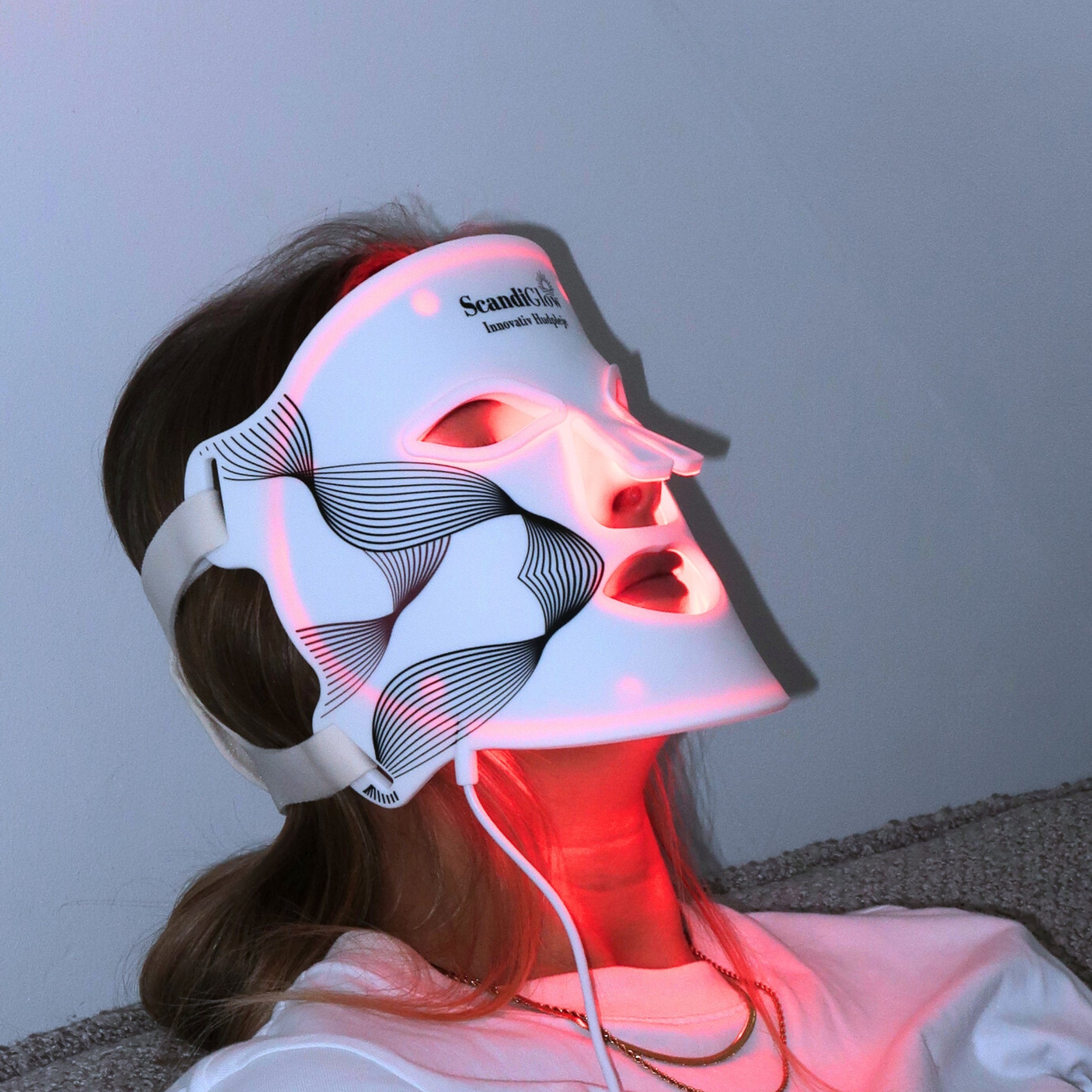 Kvinde bruger ScandiGlow LED lysterapi maske med rødt lys for sundere hud.